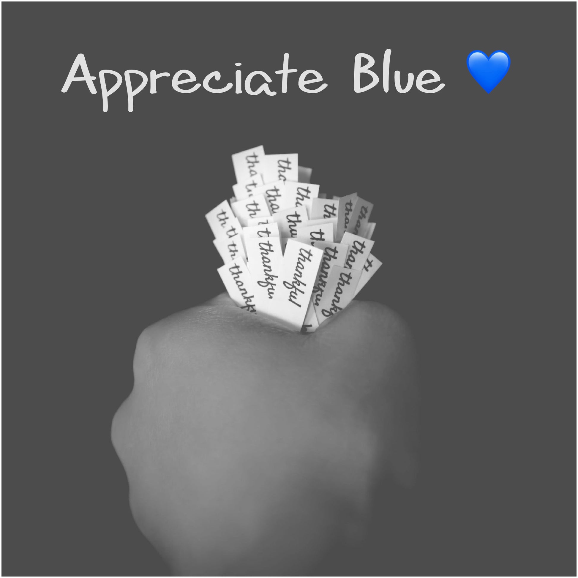 Hand holding a bunch of 'thankful' slips of paper with text 'Appreciate Blue' and a blue heart emoji on a dark background