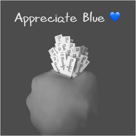 Hand holding a bunch of 'thankful' slips of paper with text 'Appreciate Blue' and a blue heart emoji on a dark background